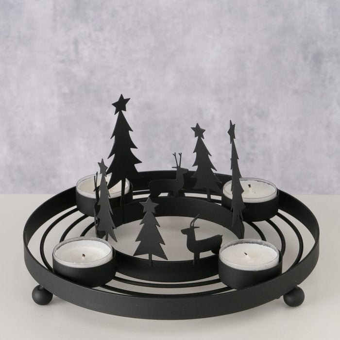 Matte black iron circular tealight wreath with cut-out Christmas tree and reindeer silhouettes holding four tealight candles, styled on a table