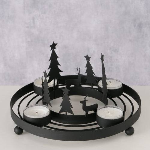 Matte black iron circular tealight wreath with cut-out Christmas tree and reindeer silhouettes holding four tealight candles, styled on a table
