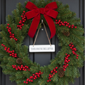 This House Believes ceramic hanging sign on a hook on a Christmas wreath-decorated dark wooden door