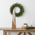 Smoked pine Santa gonk figurine on a Nordic console table with wreath, wrapped gifts, pine sprig and church candle