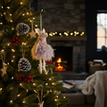 Hanging blush pink mouse in rara skirt Christmas decoration displayed on a decorated tree with warm fairy lights in a Nordic interior