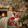 Two red fabric mice on a swing hanging on a decorated Christmas tree with warm fairy lights